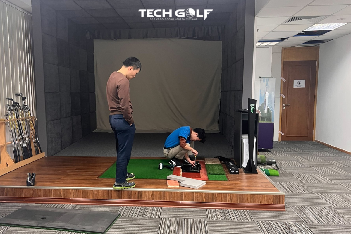 Chuyên viên kỹ thuật hỗ trợ khách hàng kiểm tra thiết bị và vệ sinh auto tee cho phòng golf 3D